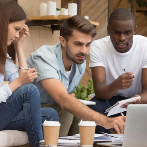 Three people sitting with coffee and looking at a laptop